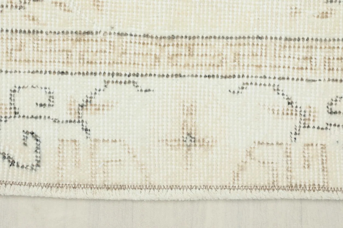 Close-up of the rug's border, revealing the geometric patterns and the texture of the wool pile.