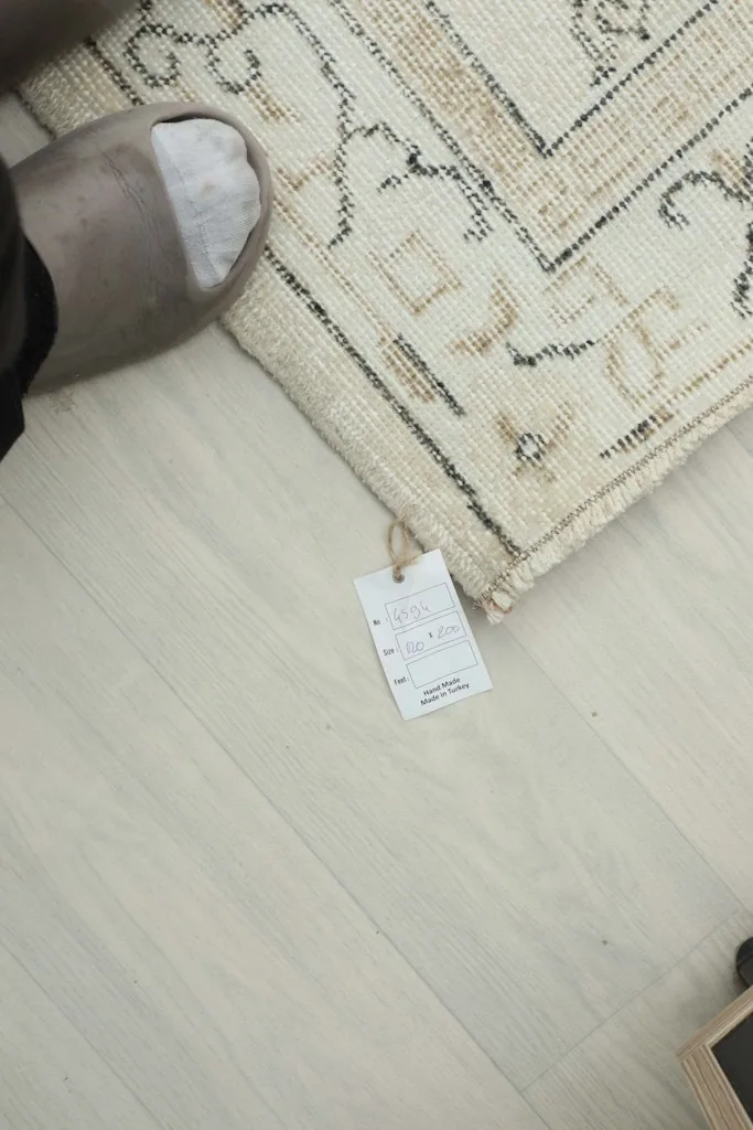 Corner of the rug with the product tag, showing the natural fringe and the hand-knotted edge.