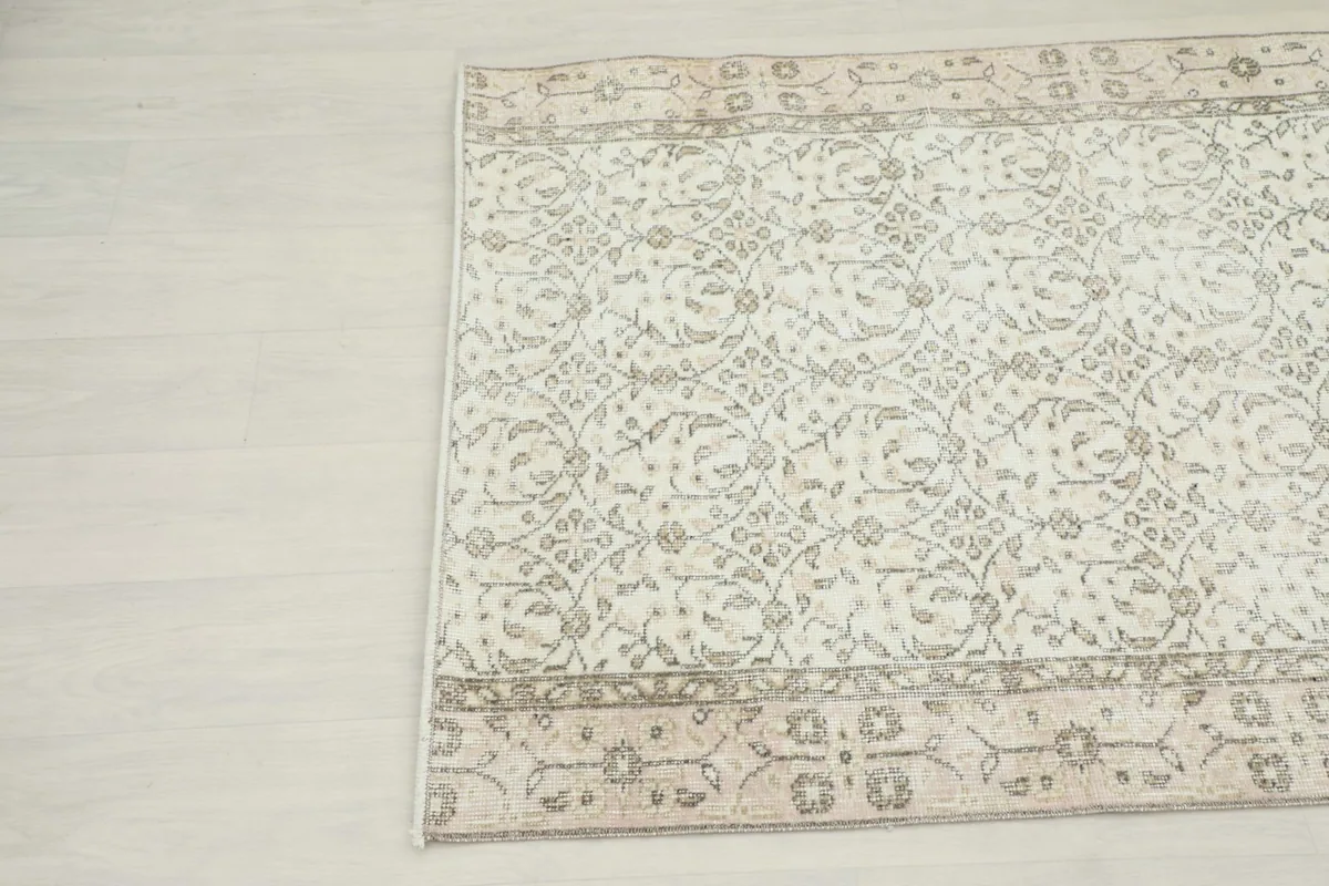 Another angle view of the vintage rug, focusing on the subtle distressing and color variations in the pattern