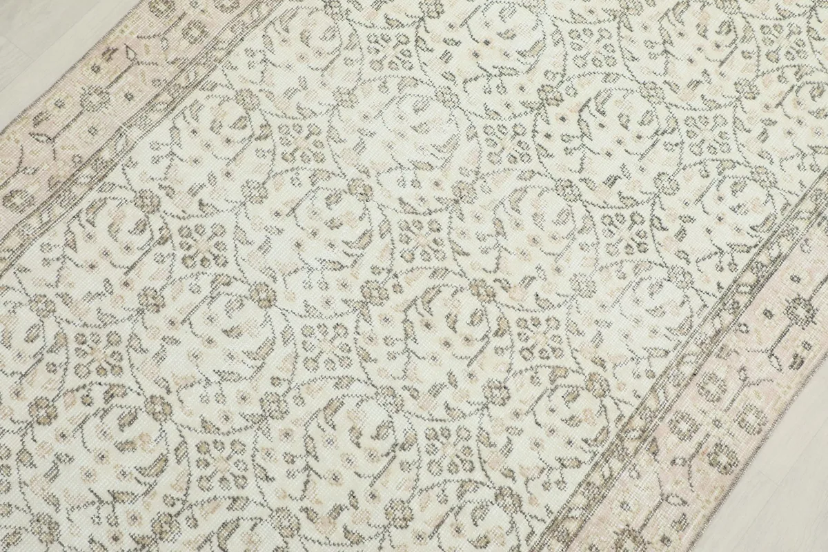 Overhead view showing the full pattern repeat and the border design of the cream and olive rug