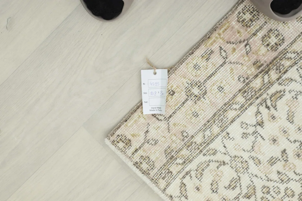 Corner of the rug with the product tag, showing the quality and origin details, next to a foot