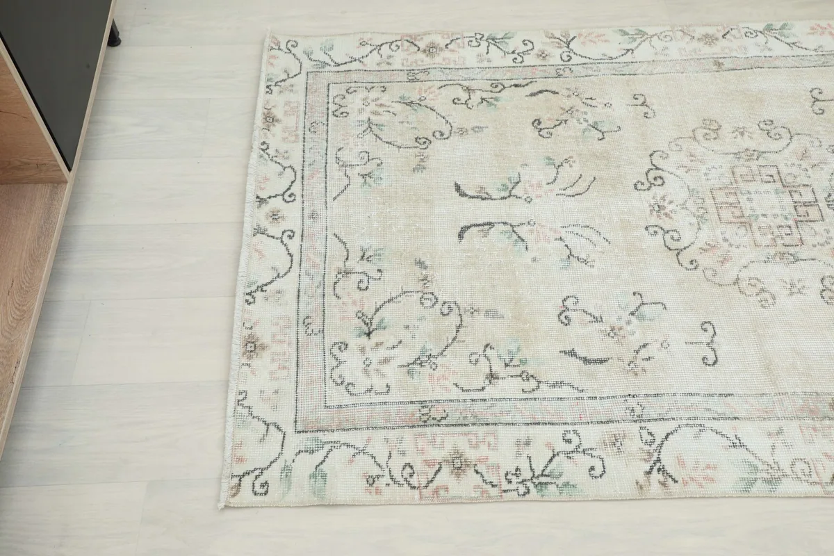 Close-up angled shot of the rug's surface, revealing the soft colors and motifs.