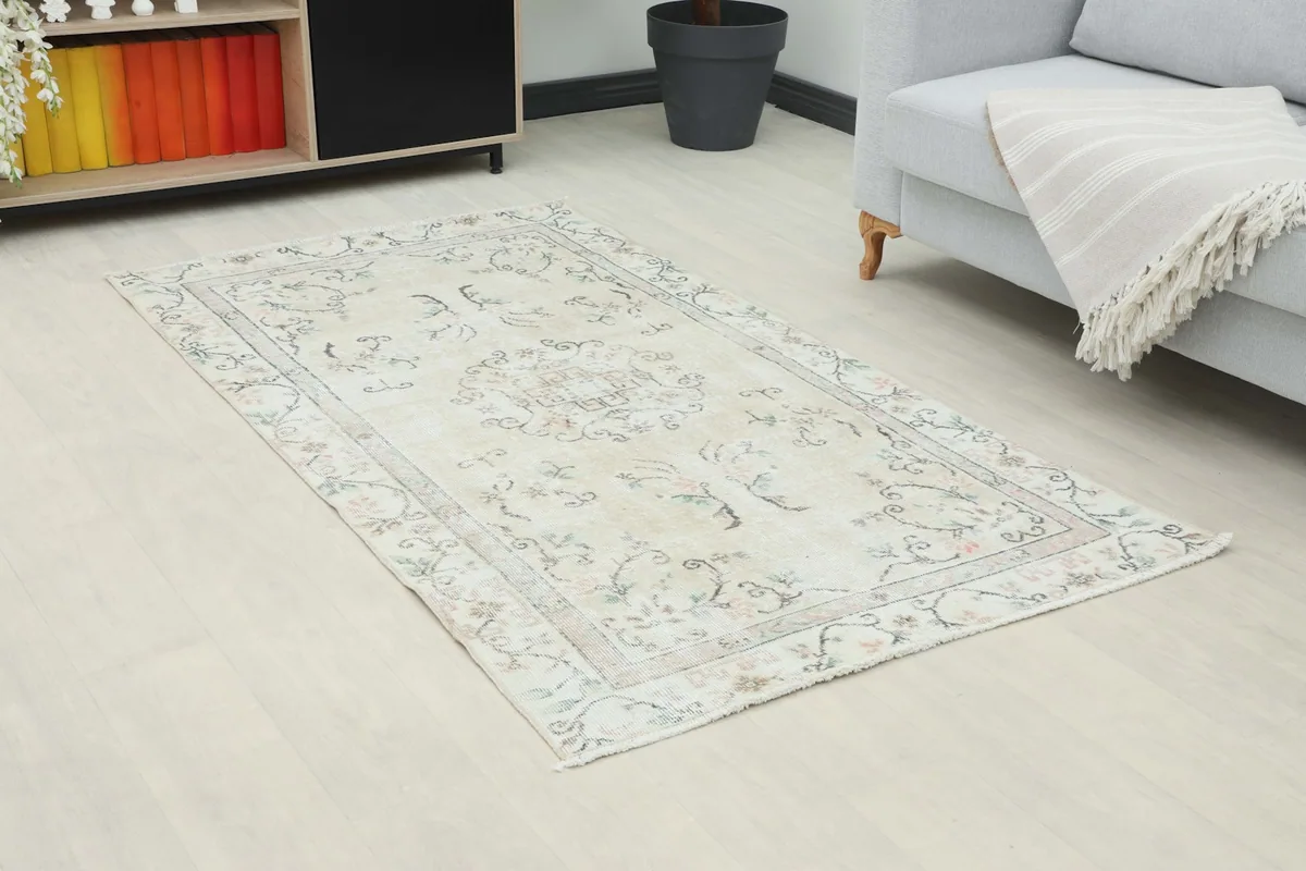Angled view of the beige rug in a room, highlighting its placement next to a sofa.