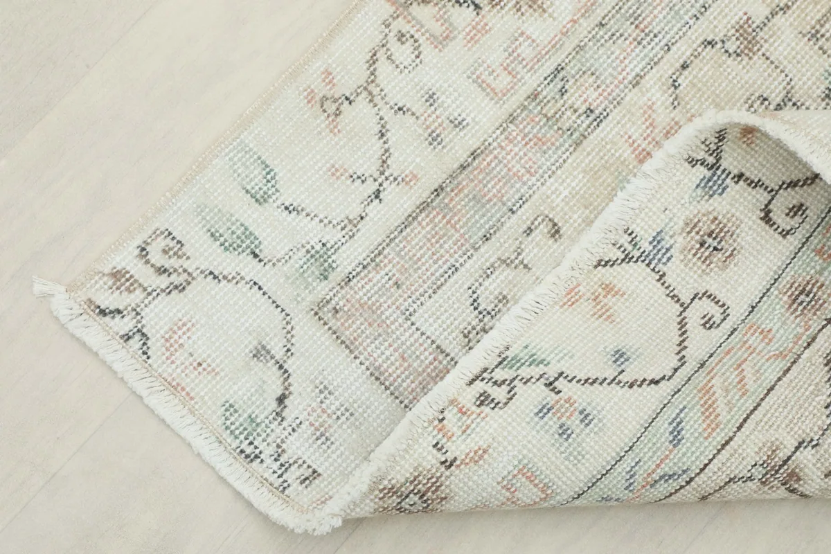 Corner of the rug folded back, showcasing the reverse side and hand knotting.