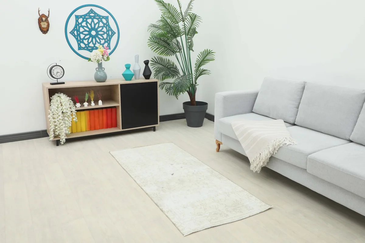 Cream beige runner rug placed in a living room setting with a sofa and cabinet