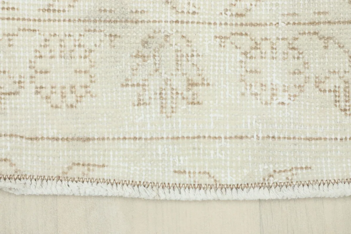 Close-up of the rug's edge showing the faded border design and short fringe
