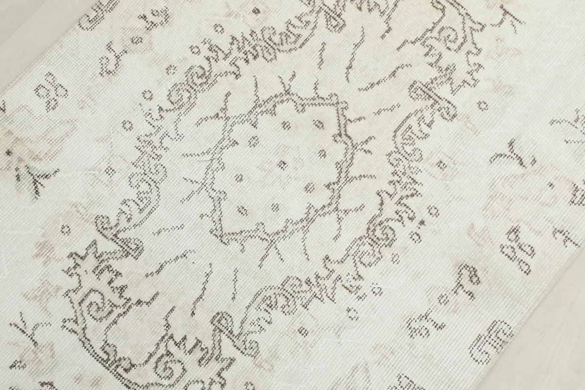 Detailed view of the central medallion pattern and surrounding designs on the ivory rug