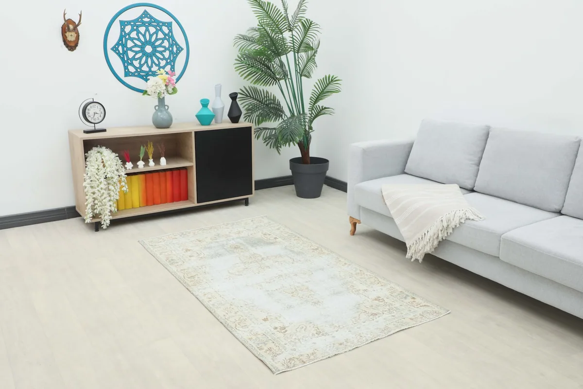 Vintage blue and beige area rug in a modern living room setting with a light gray couch and wooden cabinet