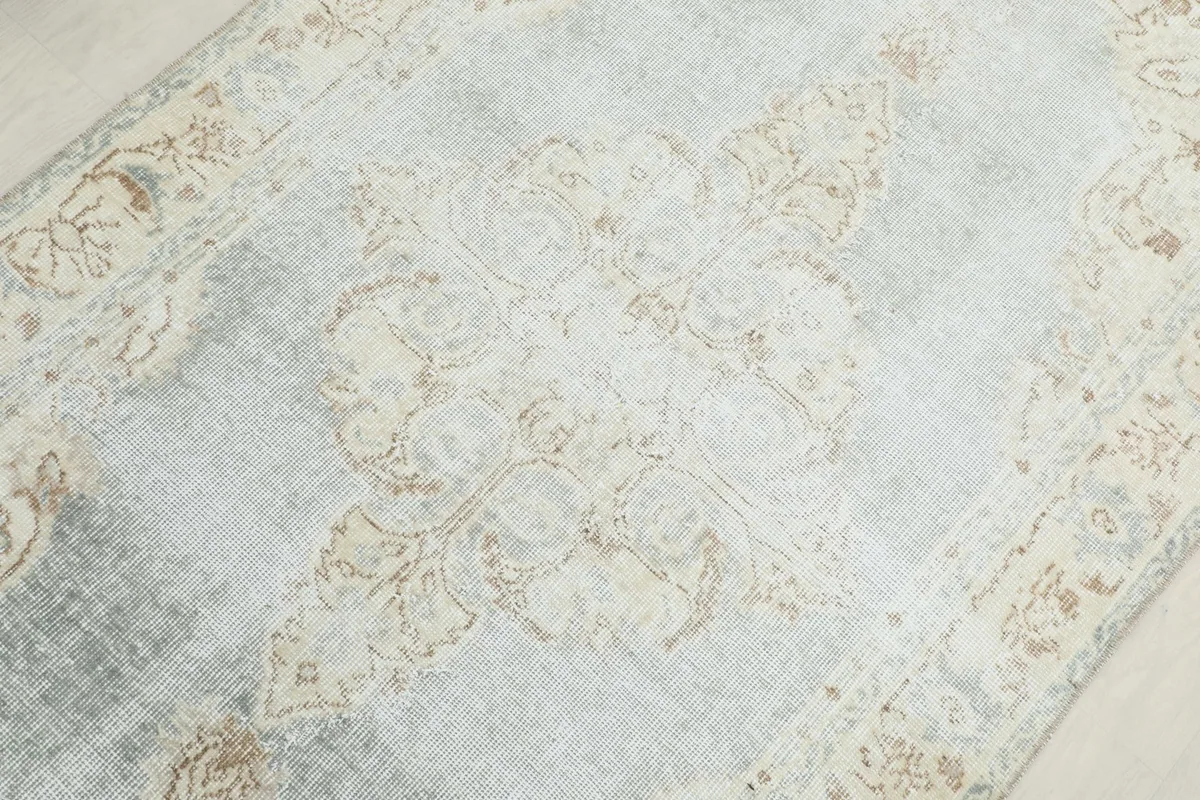 Detailed view of the central medallion and surrounding floral motifs on the blue and beige vintage rug