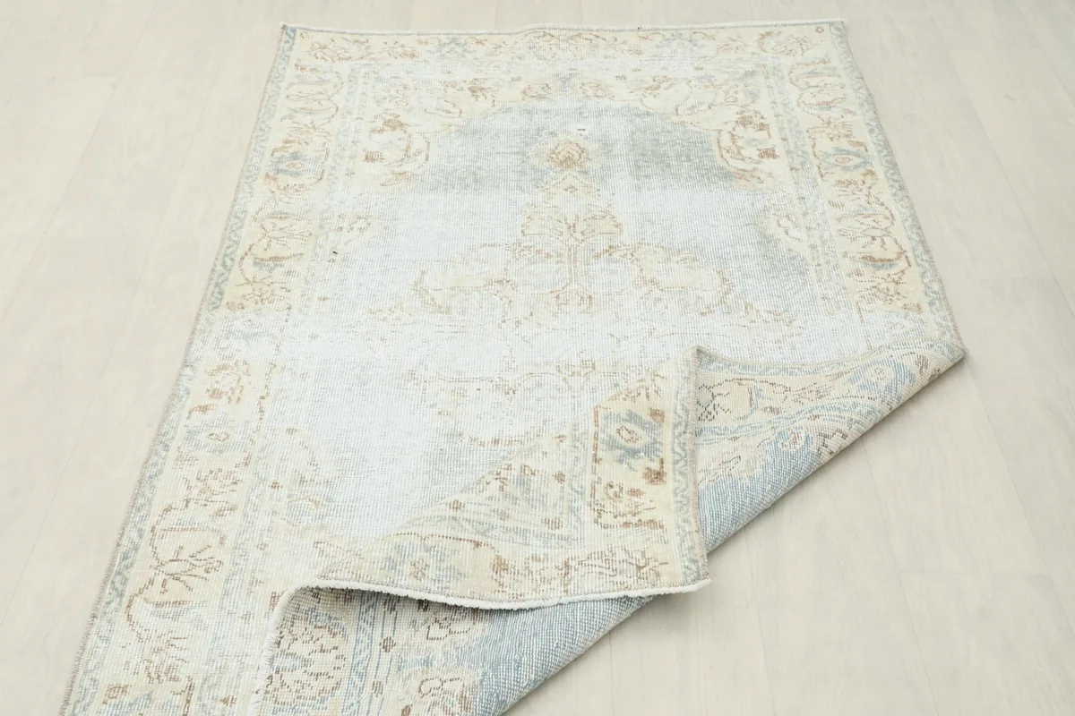 Rug partially folded, displaying the flexibility and the subtle blue and beige tones from a different angle