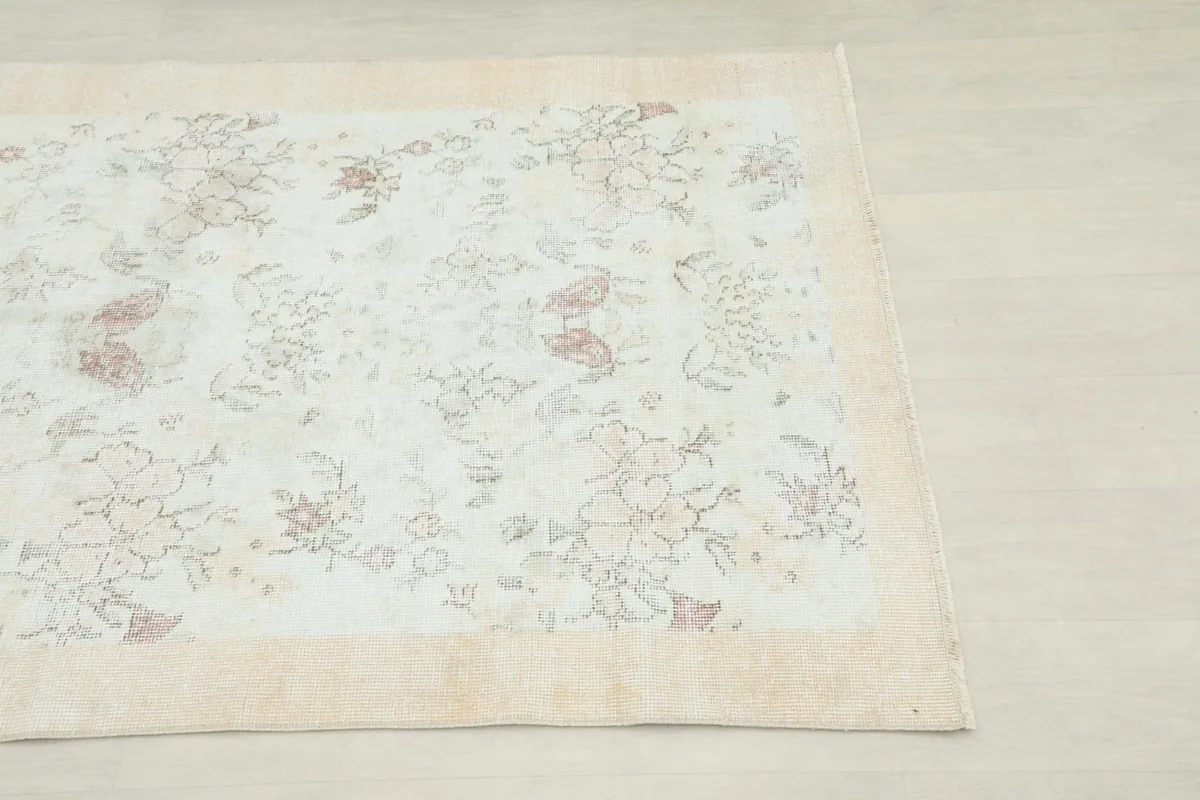 Close-up corner view of the Cream Rose Floral Vintage rug, showing the faded floral pattern and beige border.
