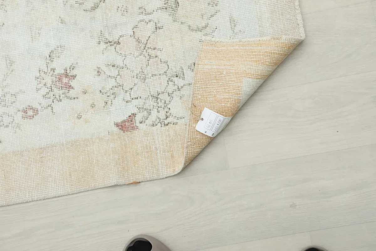 Underside detail of the rug's corner with a small label, showing the quality of the wool and cotton.