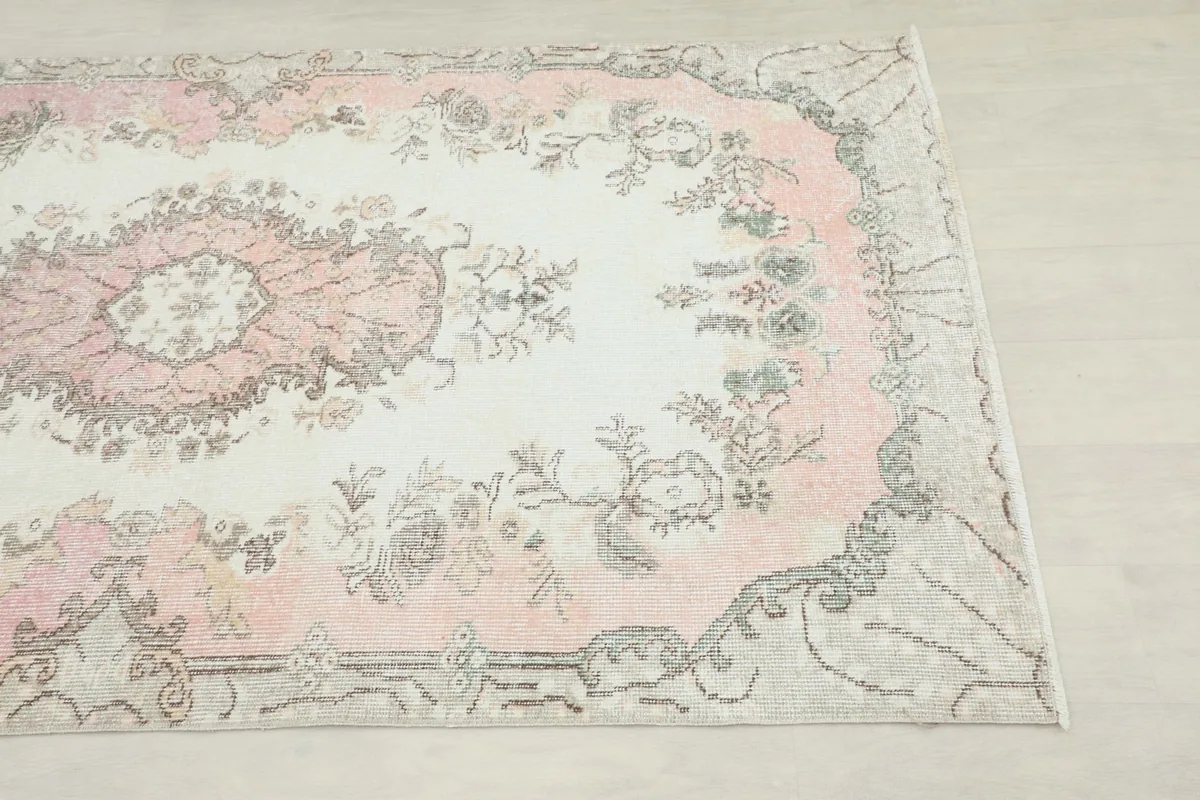 Close-up of the rug's border and corner, highlighting the gray and pink tones