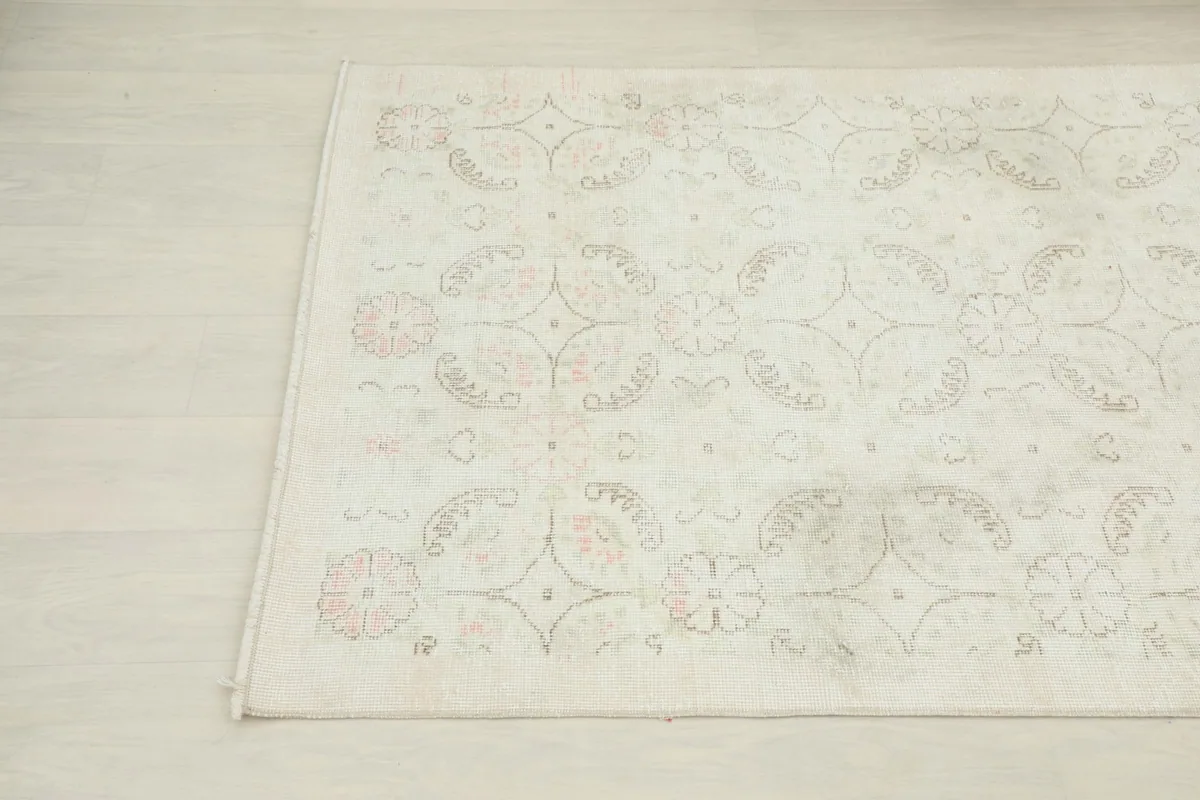 Another angled view highlighting the subtle pink and green tones within the ivory rug's pattern