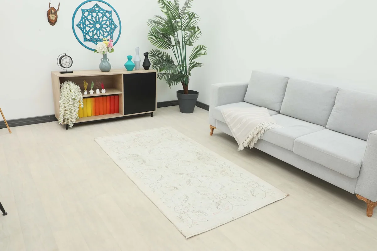 Ivory vintage rug placed in a modern living room setting next to a gray sofa