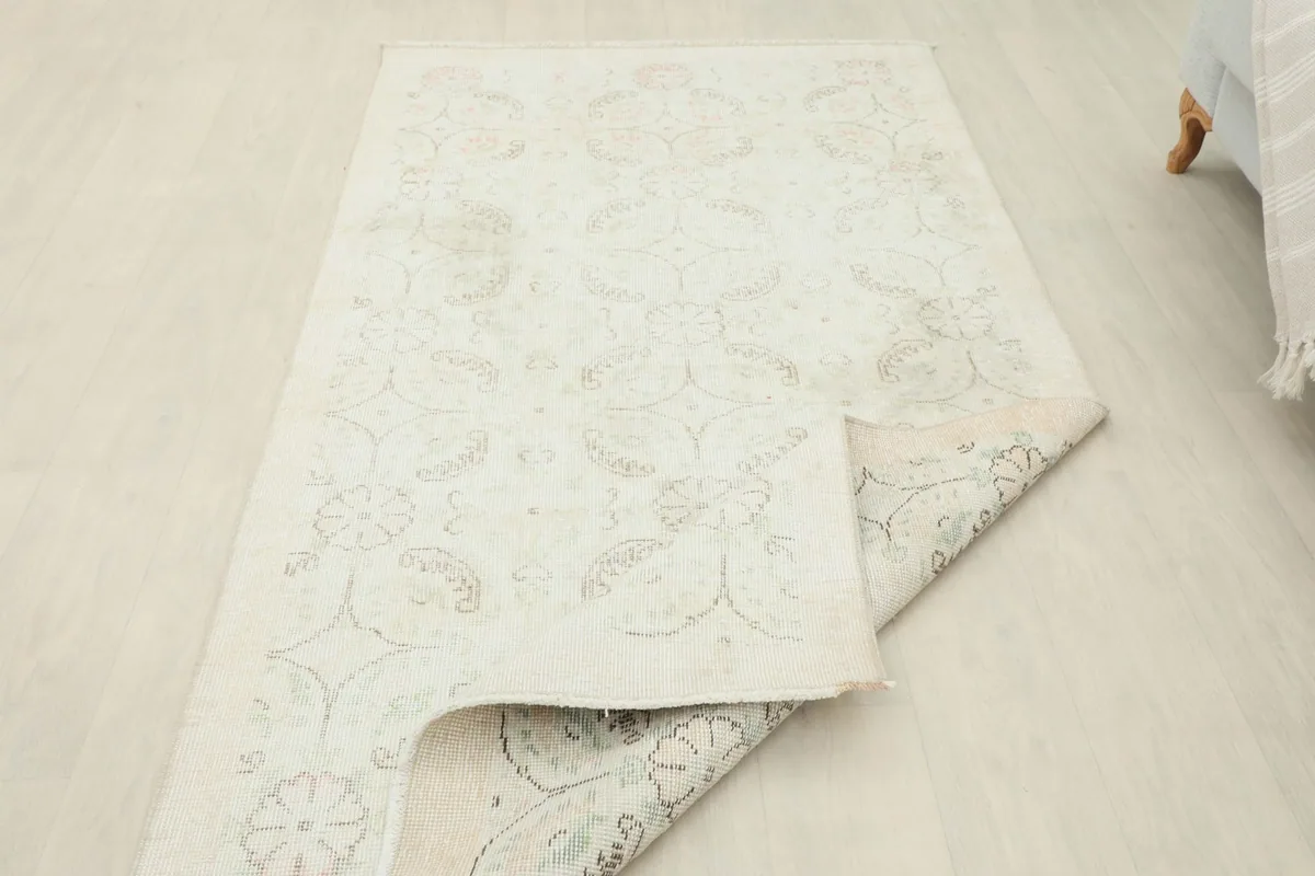 View of the rug partially folded, showing the flexibility and the reverse side of the foundation