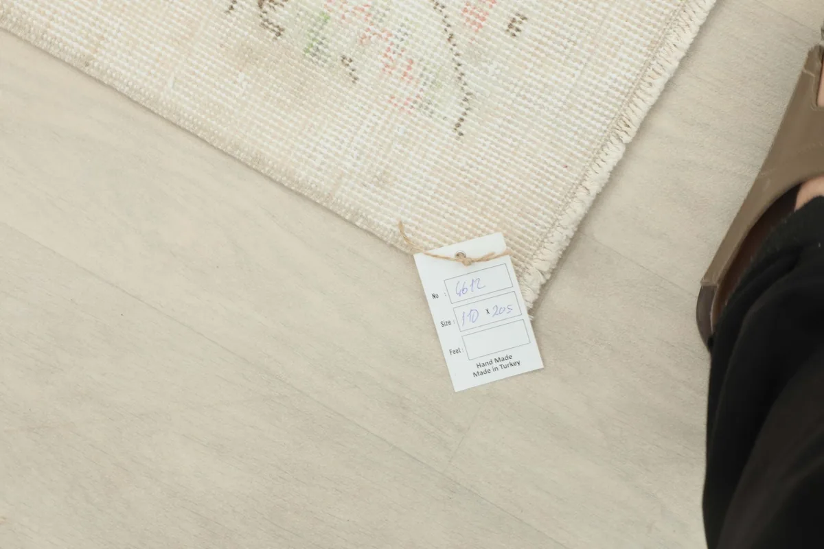 Photo of the rug's label showing its dimensions and origin, next to a foot for scale
