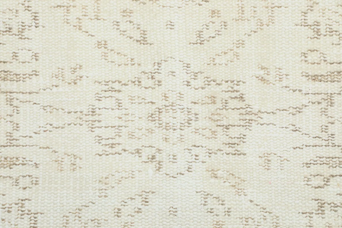 Close-up of the rug's pattern, showing the hand-knotted texture and soft ivory and tan colors.
