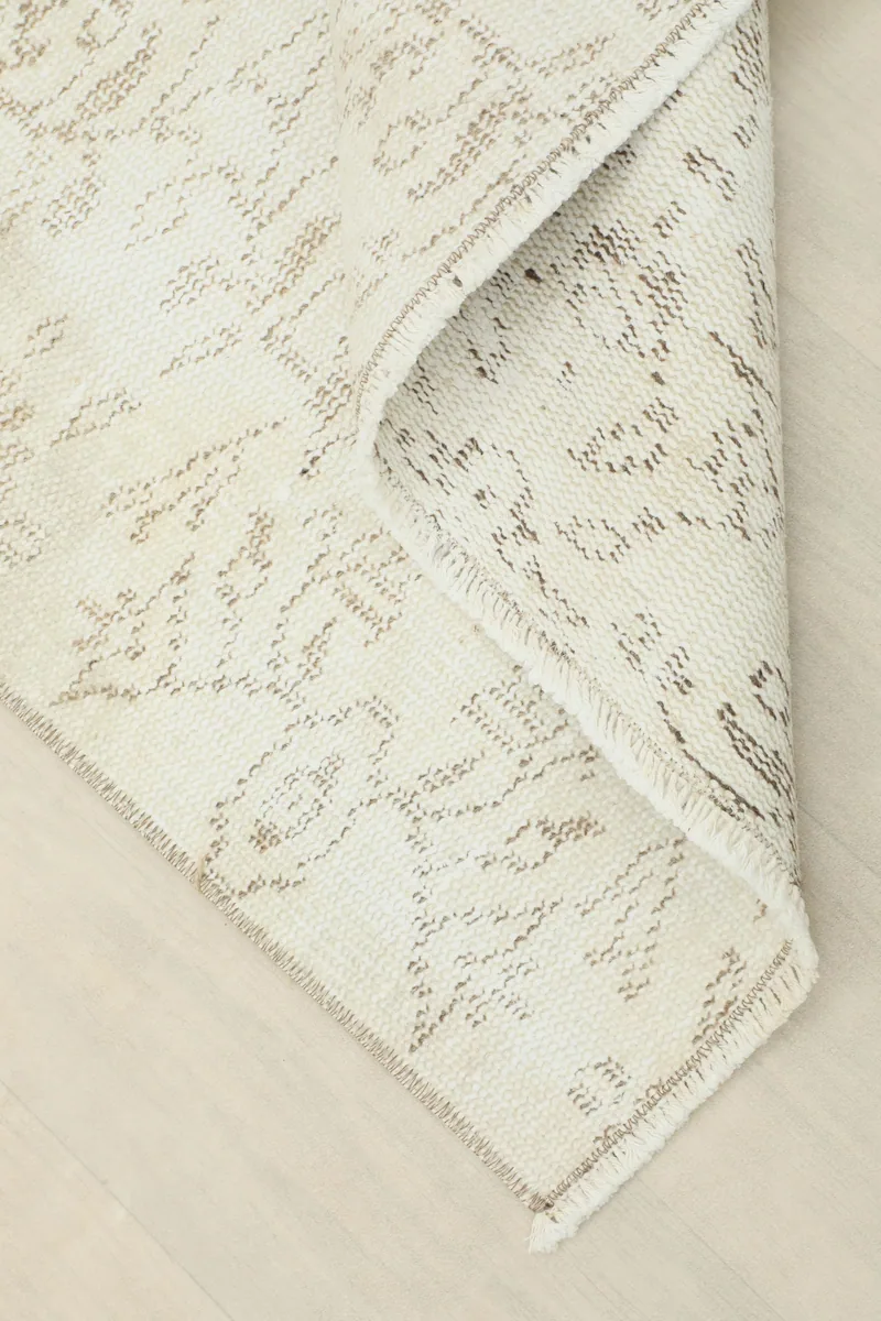 A corner of the Ivory Floral Anatolian Runner folded, revealing the wool pile and cotton foundation.