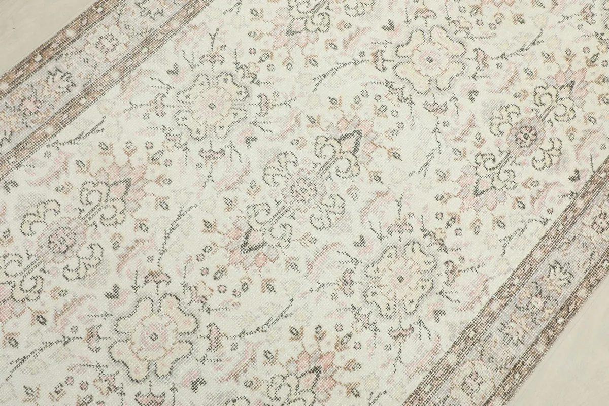 Detailed view of the rug's central design, showcasing the faded ivory and beige floral elements.