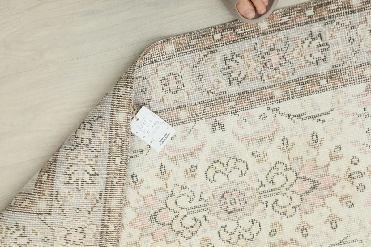 Close-up of the rug's reverse side and edge, showing the hand-knotted structure and vintage tag.