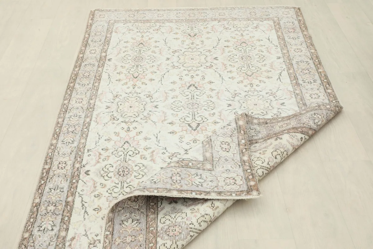 View of the rug with a corner folded, showing the distressed texture and construction.