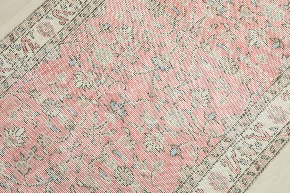 Mid-section detail of the pink rug's field, showing the intricate floral pattern and low pile.
