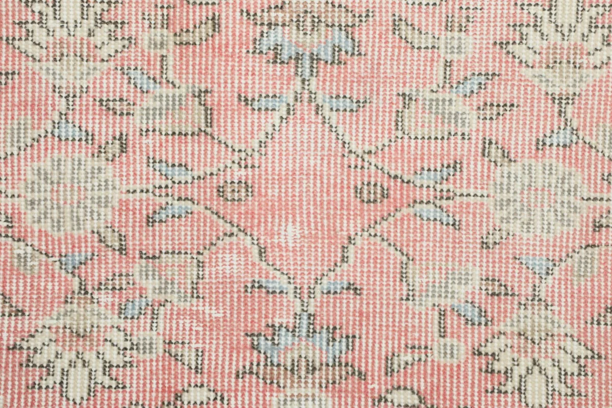 Extreme close-up of the hand-knotted pink wool pile, revealing individual knots and color blend.