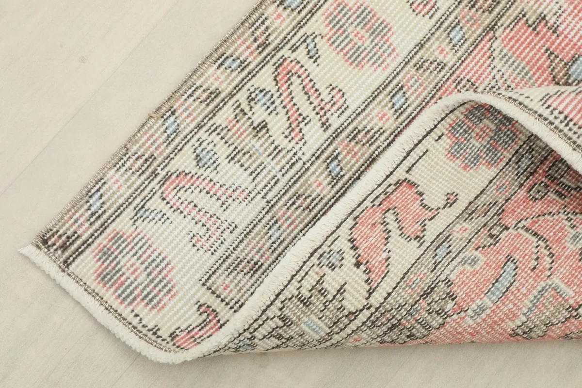 View of the rug's reverse side and folded edge, showing the cotton foundation and knotting.