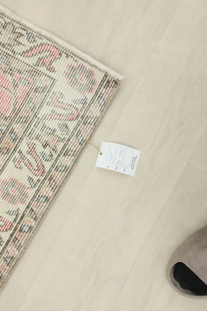 Overhead view of a corner of the rug with a product tag, showing the reverse side and fringes.