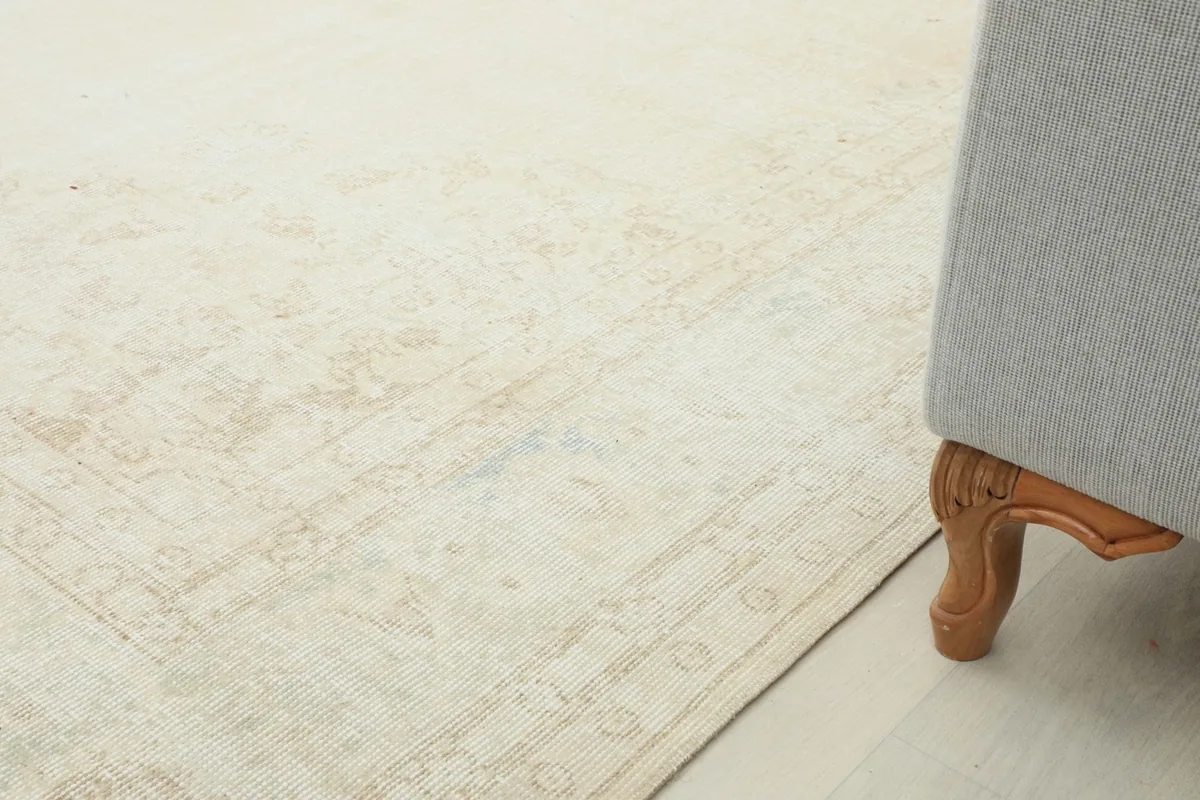 Corner view of the rug next to a sofa leg, showing the border design and low pile
