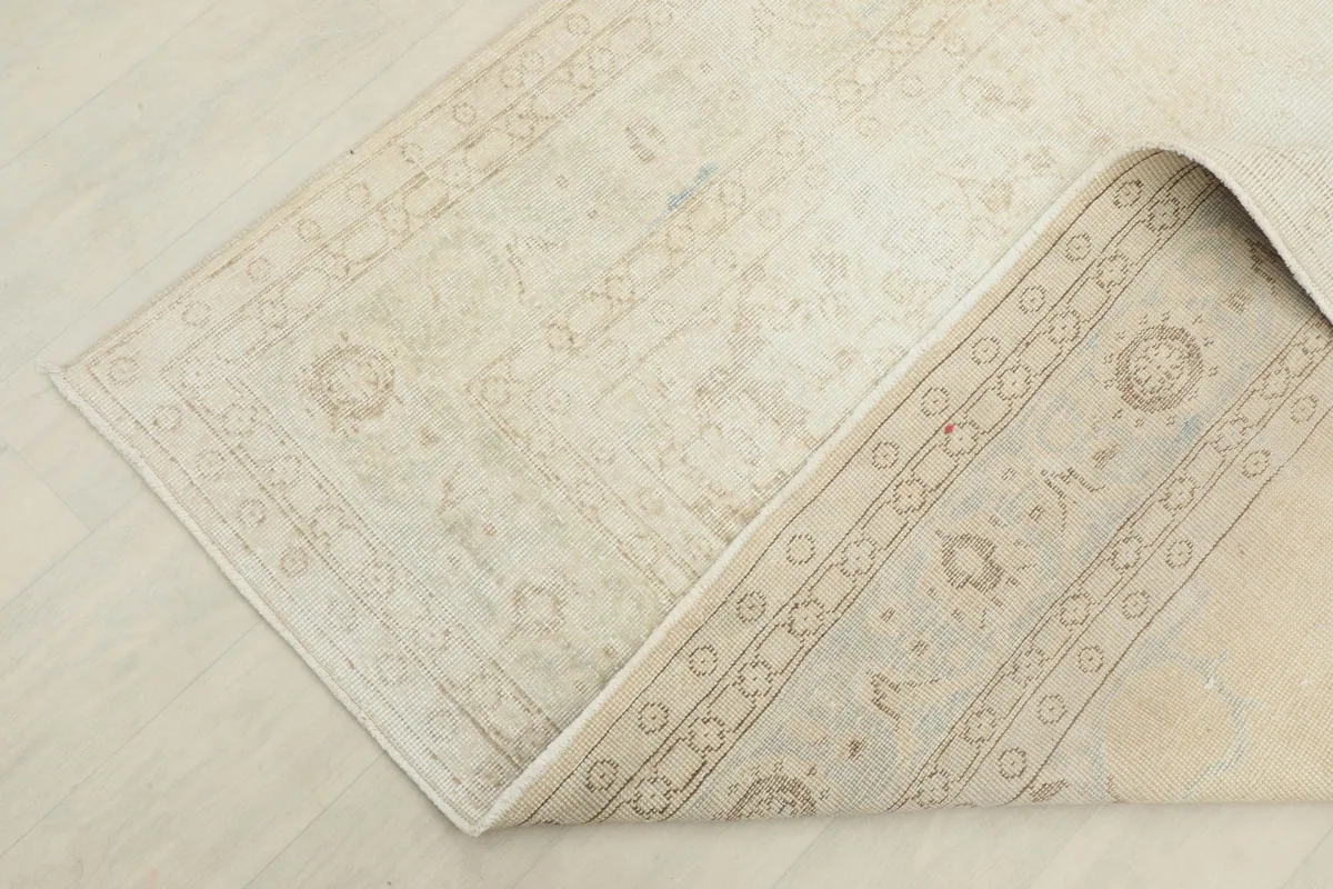 Corner of the ivory rug folded back, showing the back of the rug and the reverse of the pile
