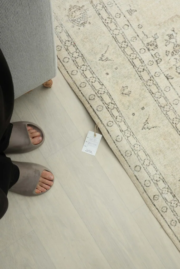 Person's feet next to the rug, showing scale and the rug's tag near the border