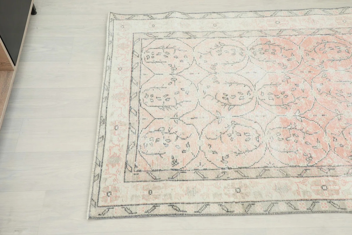 Overhead angle highlighting the faded rose tones and intricate border details of the vintage rug