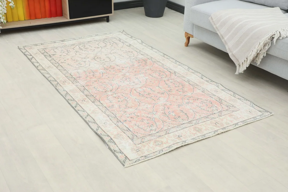 Angle view of the small rose and ivory geometric rug complementing a light-colored room