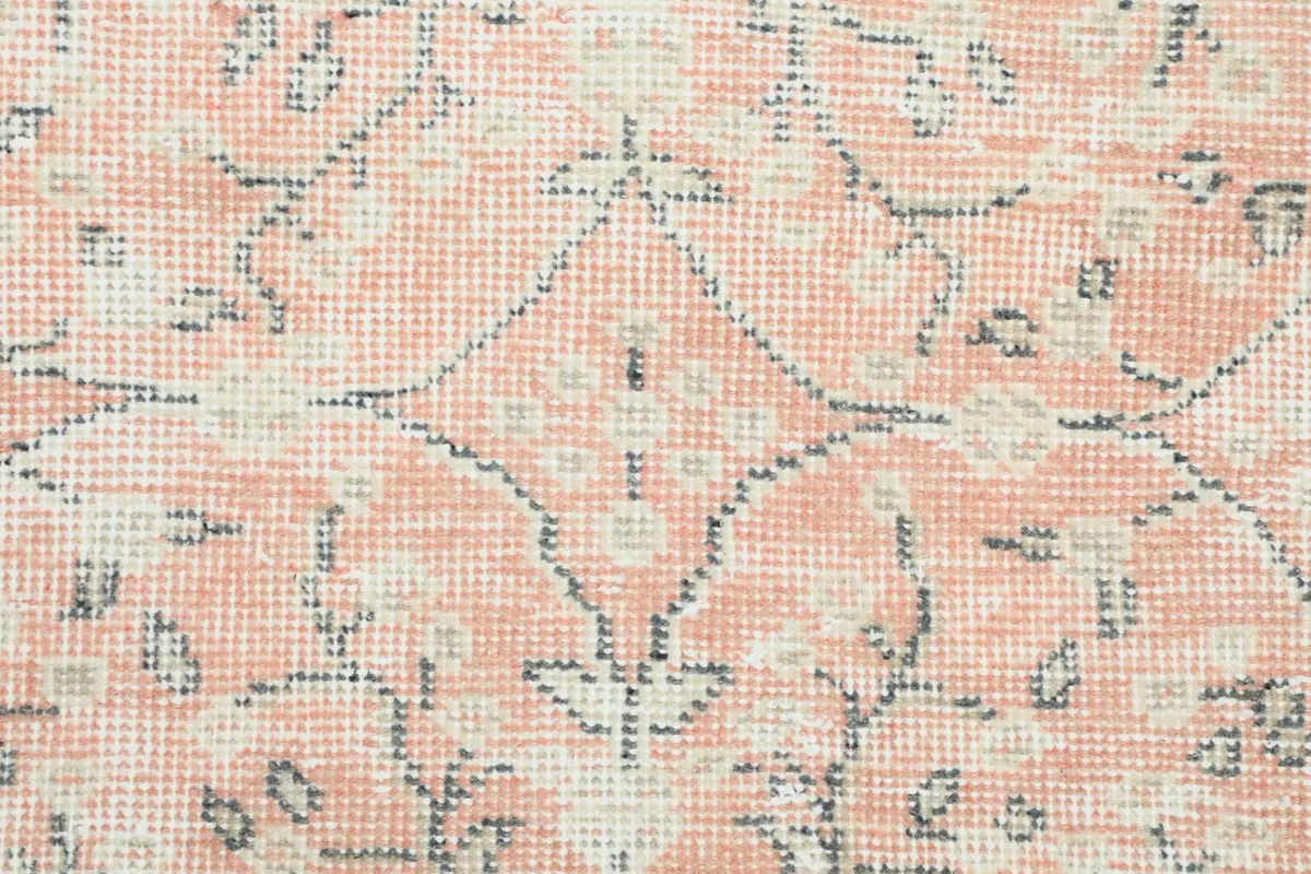 Close-up of the hand-knotted wool pile, showing the texture and faded rose and ivory threads