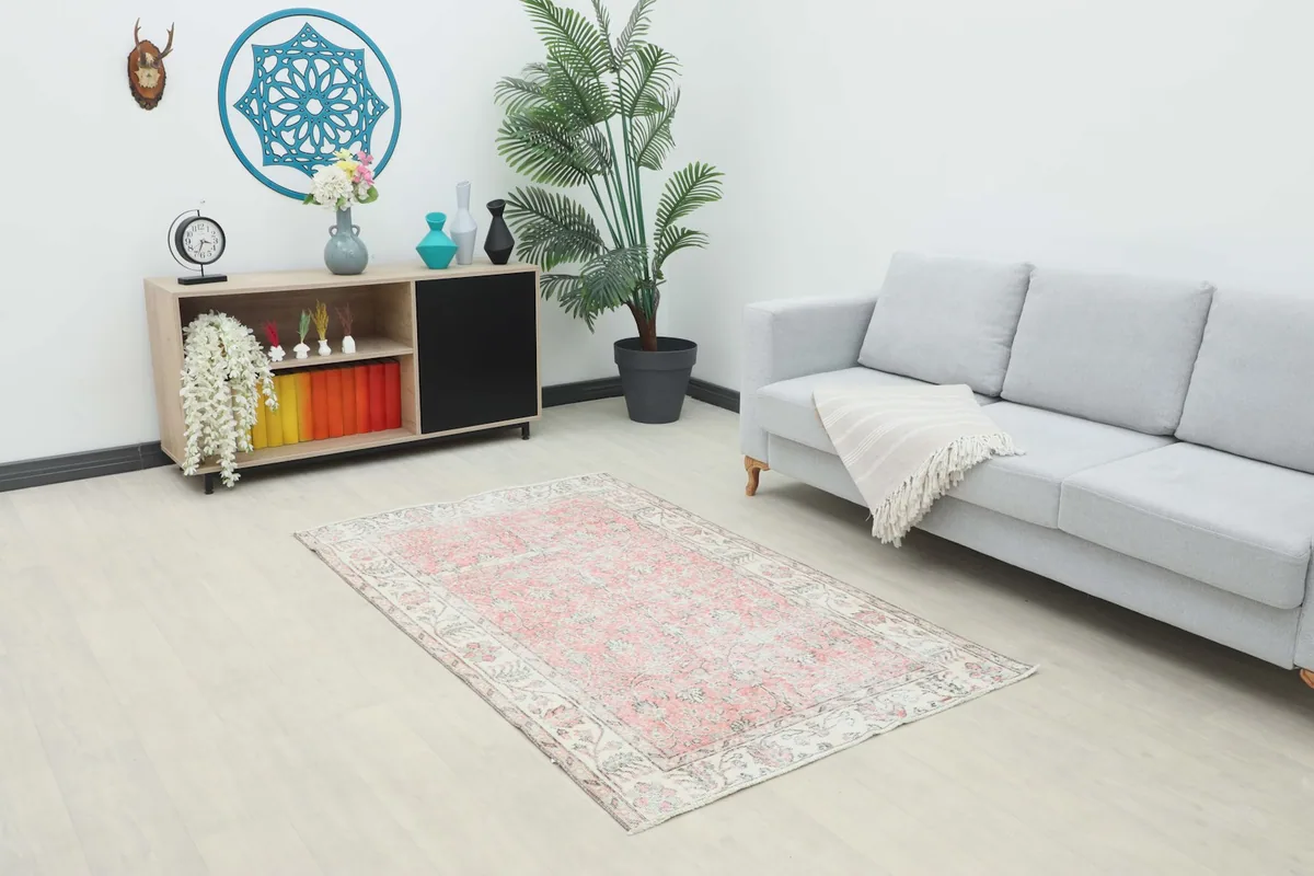 Vintage pink and ivory rug placed in a modern living room setting with a light gray sofa.
