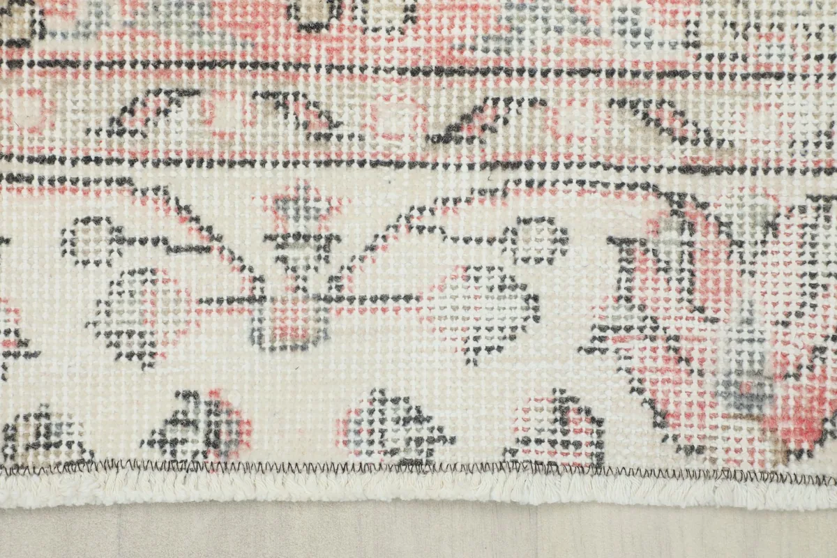 Close-up view of the rug's border design and fringe, showing the wool pile and cotton foundation.