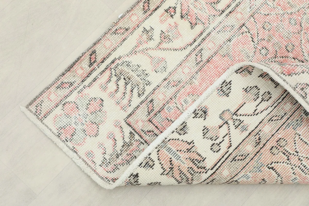 Corner of the rug folded back, revealing the reverse side and the tight hand-knotted construction.