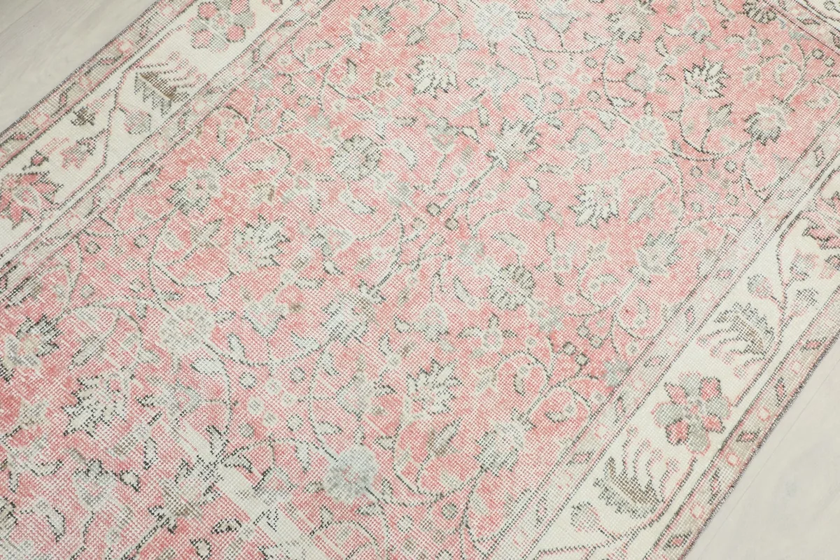 Detailed overhead view focusing on the central floral motifs and faded pink color of the rug.