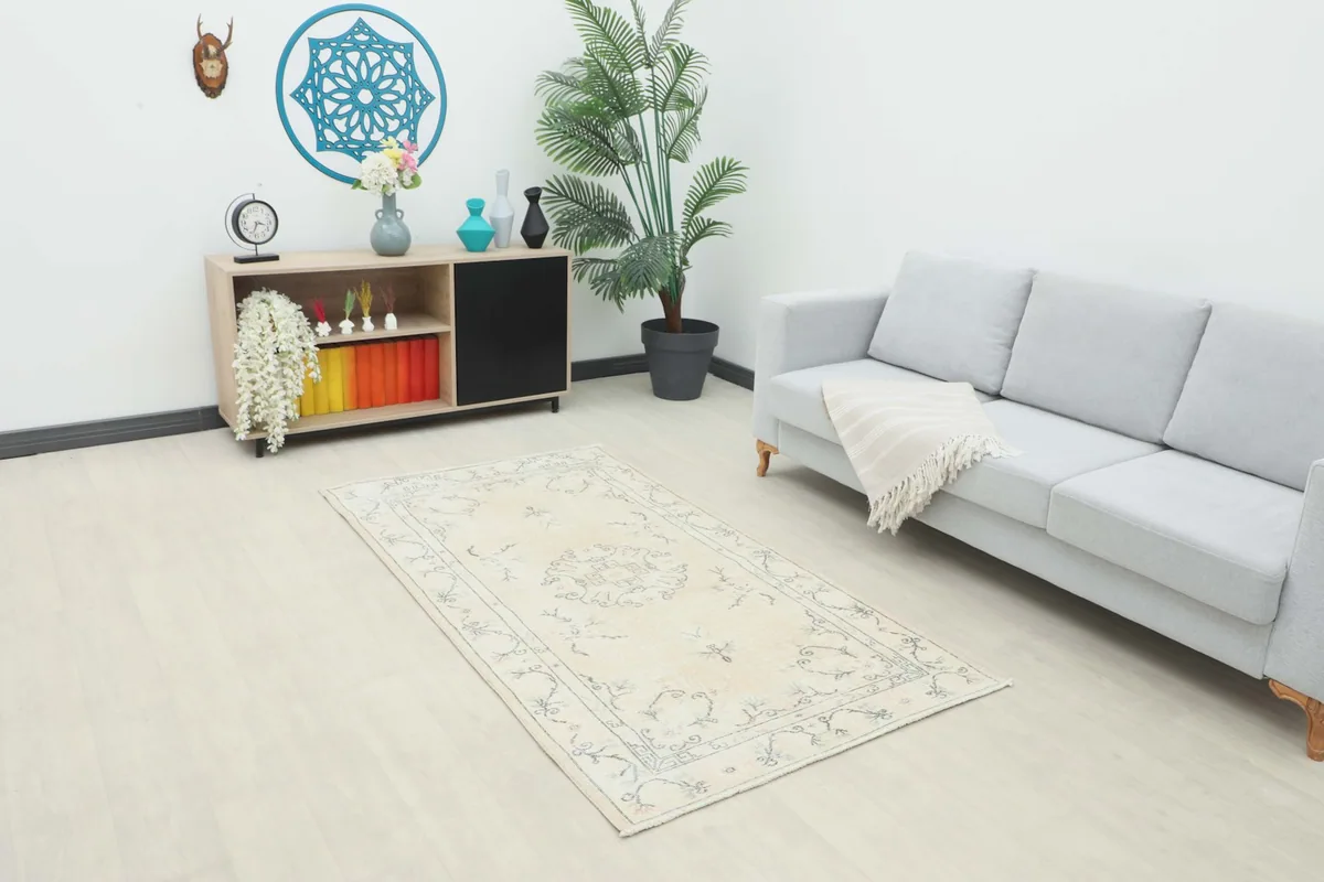 Cream and gray vintage Anatolian rug placed in a living room setting with a light gray sofa.
