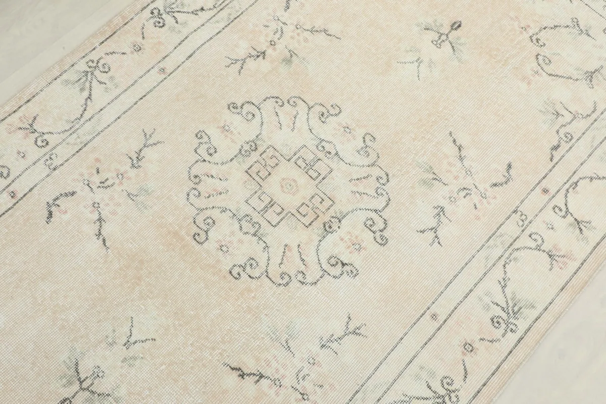 Central detail of the rug, focusing on the stylized gray medallion motif and surrounding floral elements.