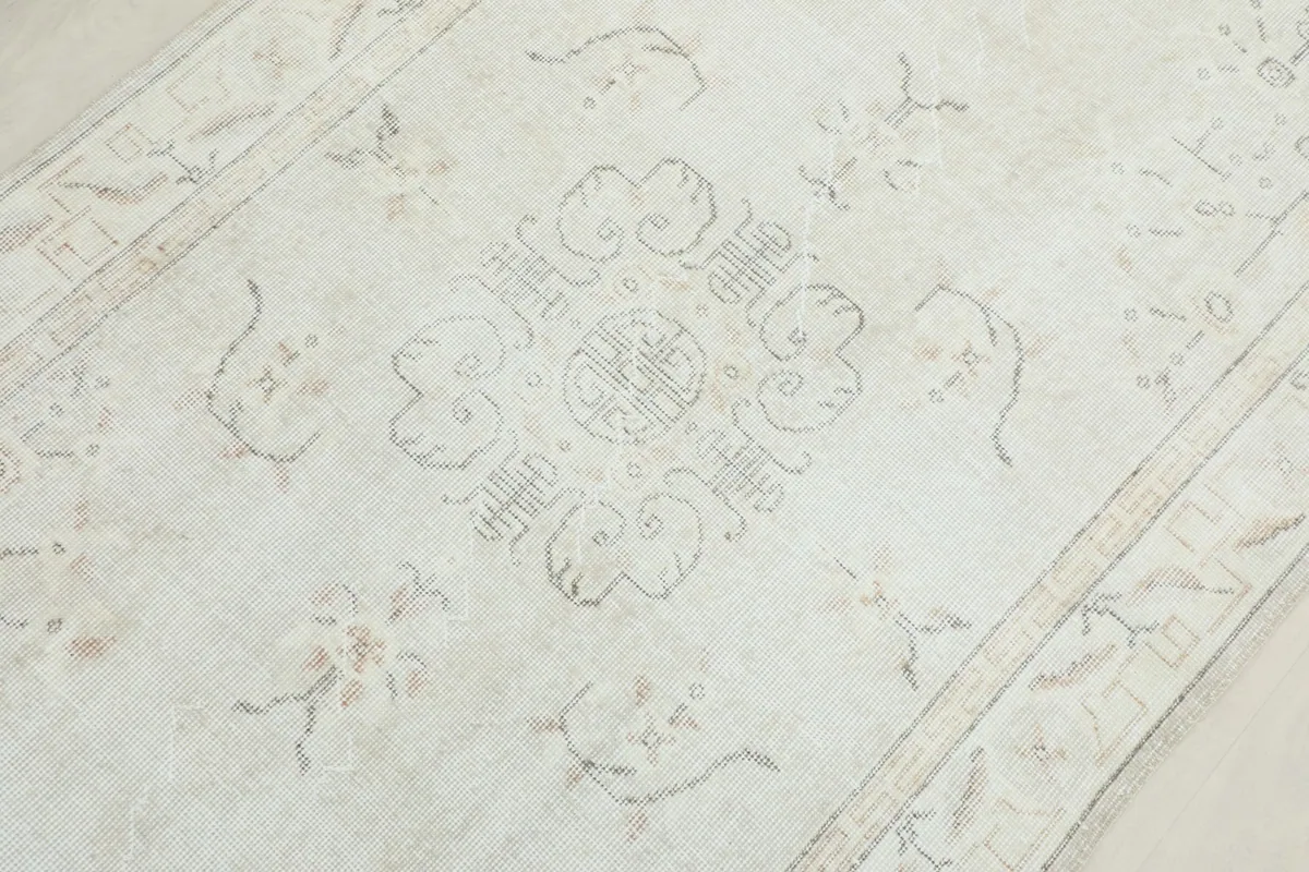 Detailed view of the central medallion motif and surrounding patterns on the ivory rug