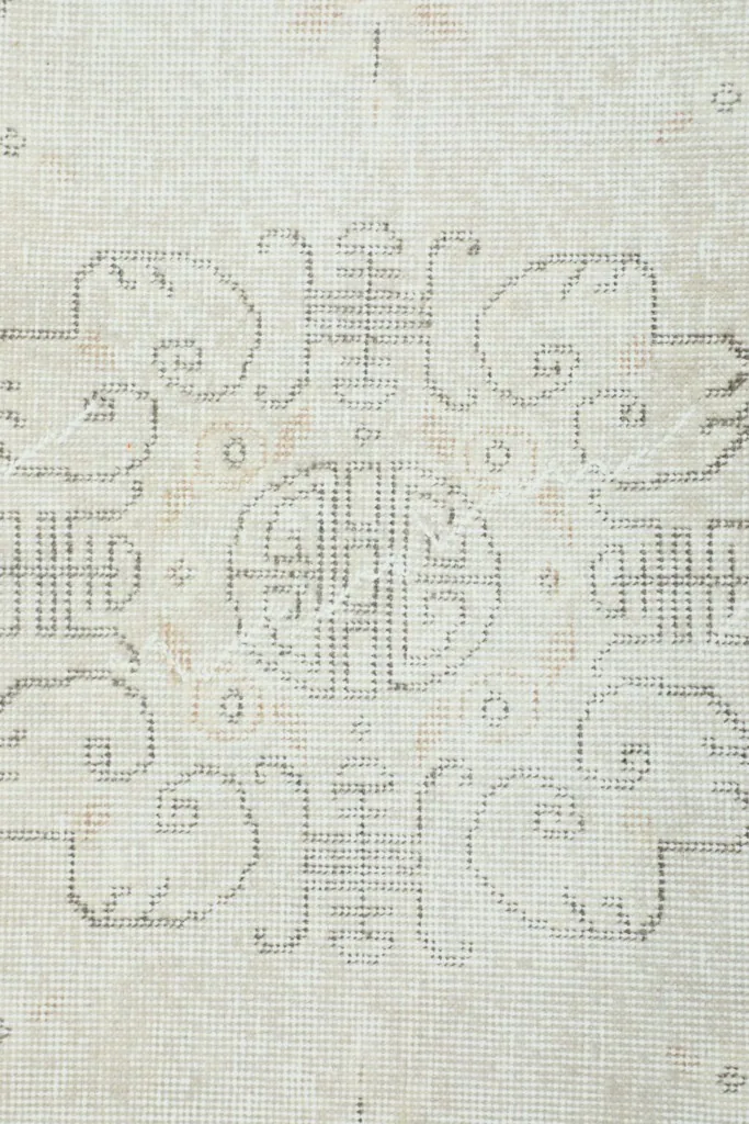 Close-up showing the low pile texture and intricate knotting of the ivory wool rug