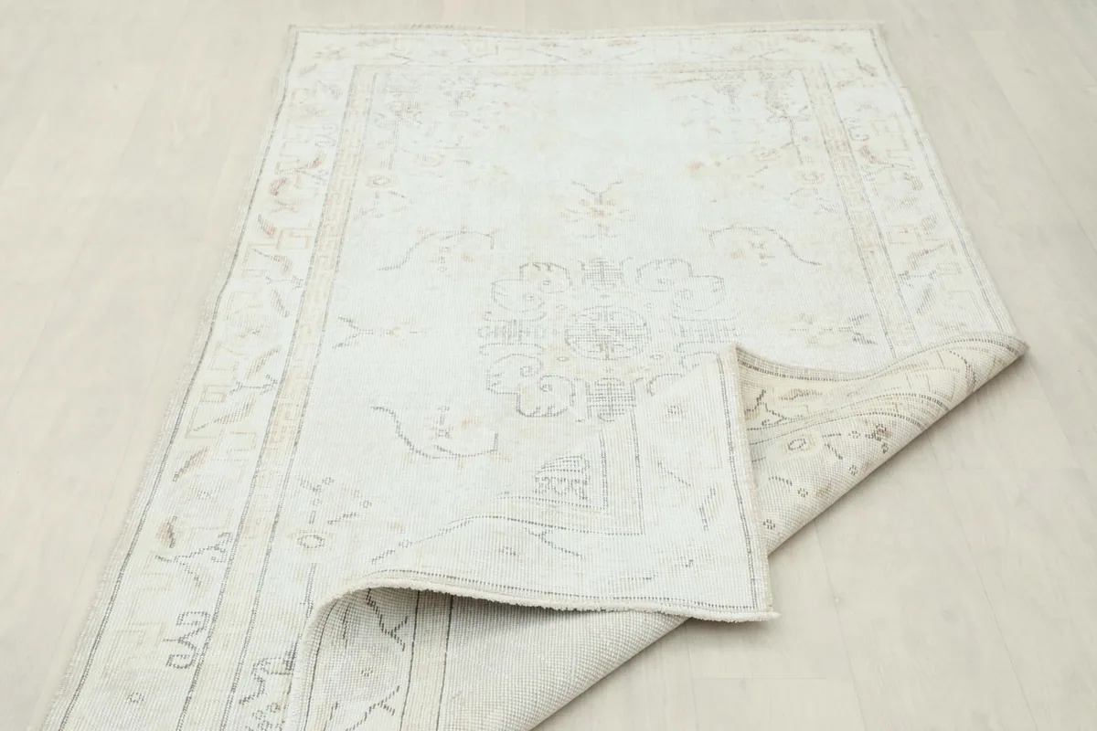 Partial view of the rug with a corner folded, displaying the reverse side and original condition