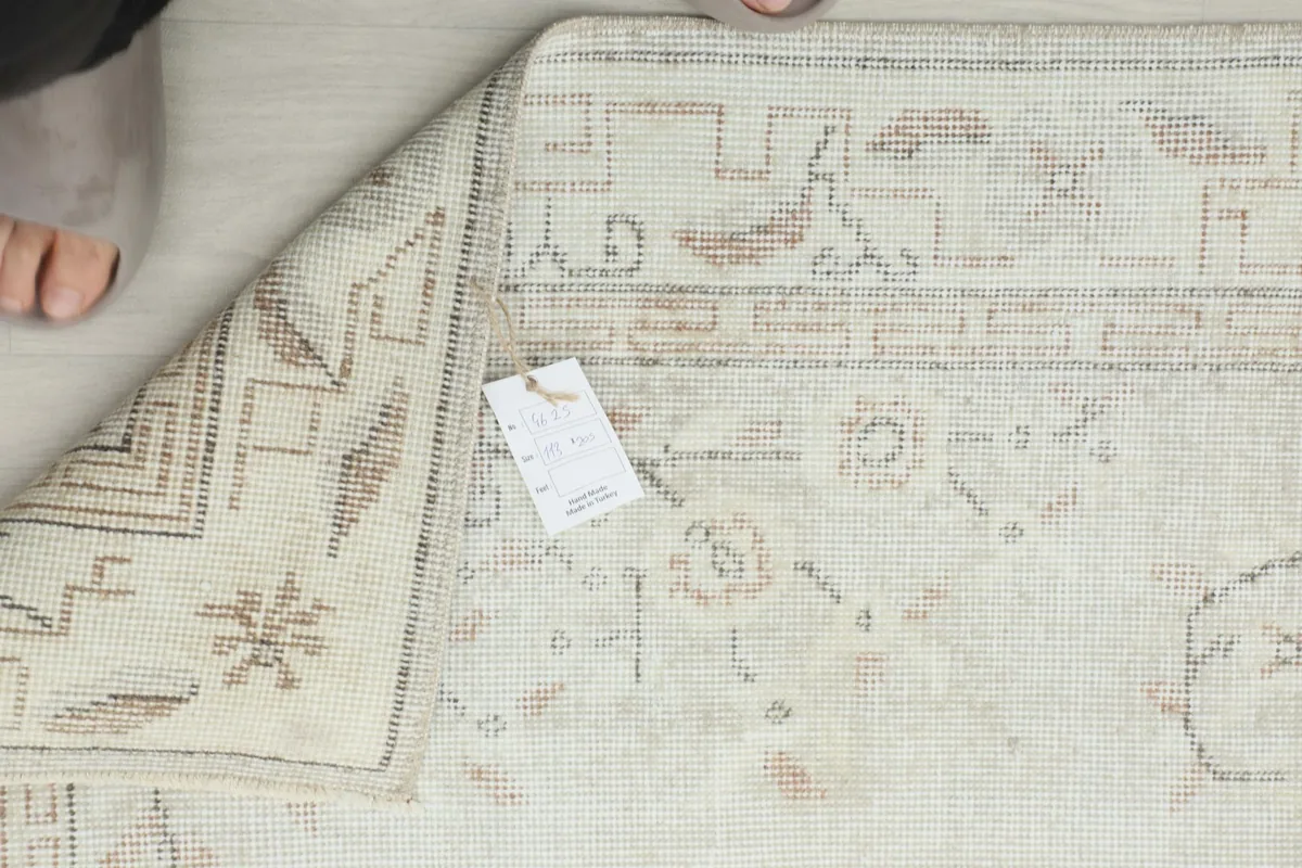 Underside of the rug with a label, showing the hand-knotted details and fringe