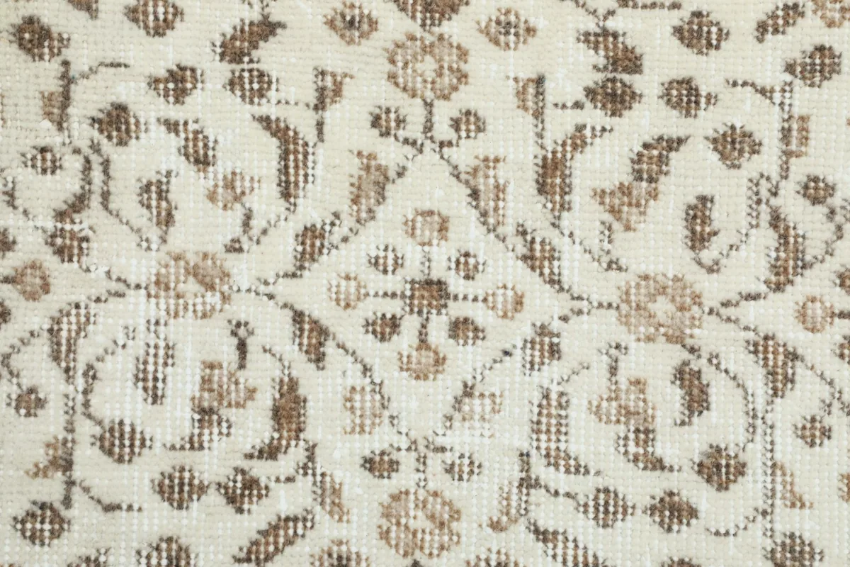 Detailed view of the low wool pile texture and the faded brown floral motifs
