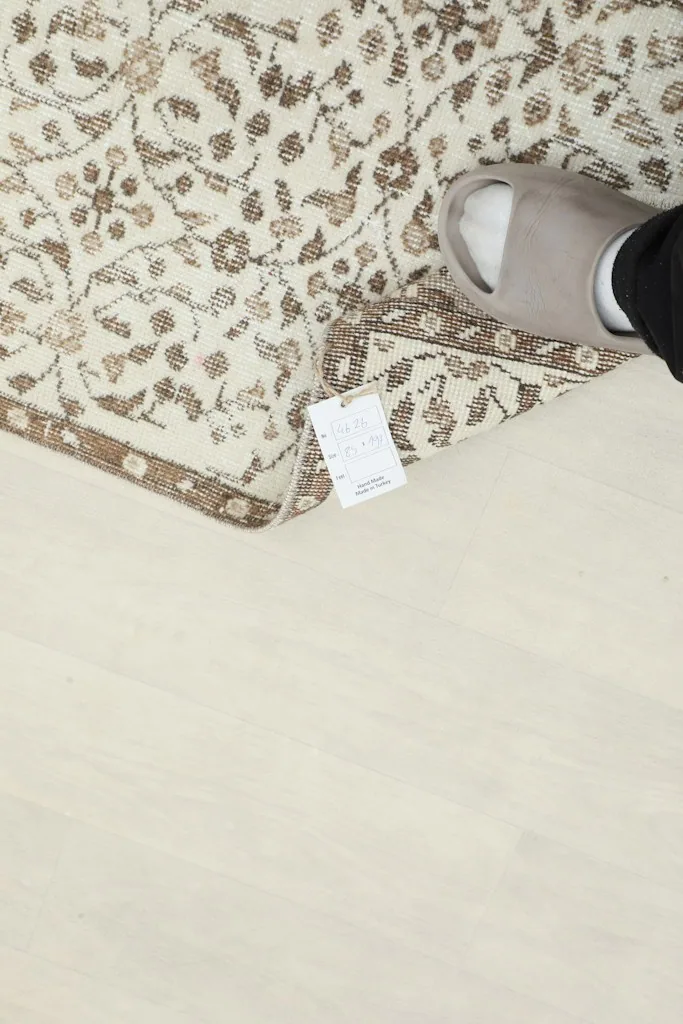 Foot next to the folded rug, indicating the scale and showing a small label