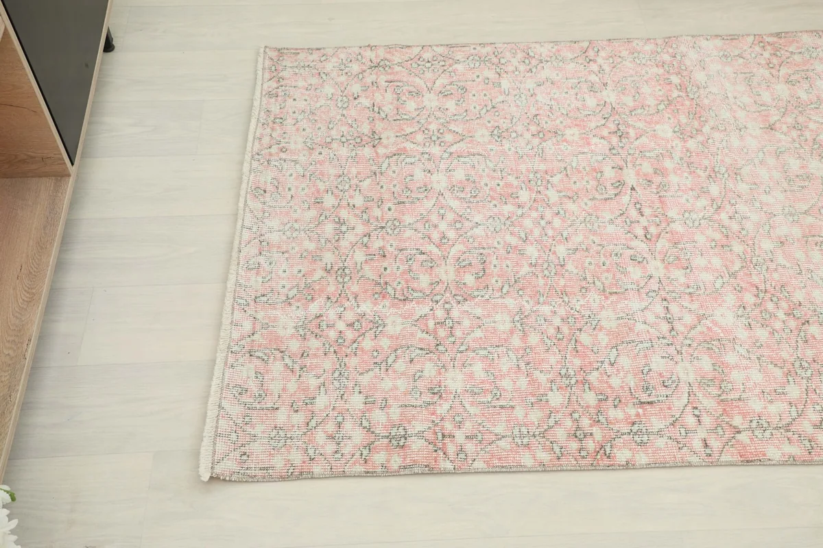 Detail of the rug's pattern and texture, with soft rose, gray, and beige tones visible.