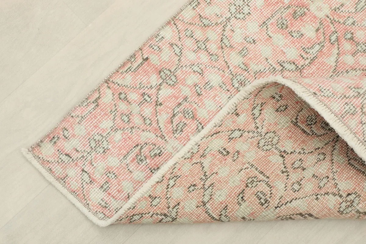 Corner of the rug folded to show the cotton foundation and the reverse side of the hand-knotted construction.